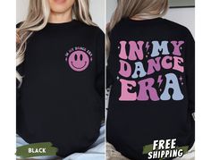 Dance into nostalgia with our 'In My Dance Era' sweatshirts and hoodies! Featuring a vibrant purple/pink/blue retro groovy font on the back, these tops exude retro charm and dance floor vibes. The front pocket design boasts the phrase 'In My Dance Era' in a groovy font, accompanied by a graphic of a retro smiley face, adding a fun and playful touch to your garment. Whether you're hitting the dance studio or lounging at home, these sweatshirts and hoodies are the perfect blend of style and comfor Hip Hop Sweatshirt With Letter Print For Concert, Hip Hop Long Sleeve Sweatshirt For Dance, Cotton Graphic Print Sweatshirt For Dance, Long Sleeve Letter Print Sweatshirt For Dance Class, Casual Graphic Print Sweatshirt For Dance Class, Graphic Print Crew Neck Sweatshirt For Dance, Graphic Print Long Sleeve Sweatshirt For Dance, Crew Neck Graphic Print Sweatshirt For Dance, Relaxed Fit Sweatshirt With Letter Print For Dance Class