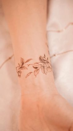 a woman's hand with a flower tattoo on her left wrist and the other arm