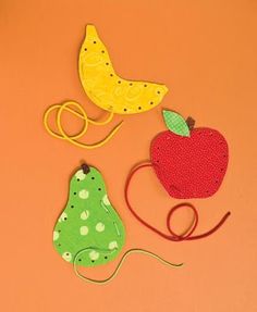 an orange background with three pieces of felt and two bananas, apple, and pear