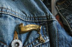 a harry potter badge is attached to a jean jacket with a keychain on it