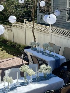 an outdoor dining area with blue table cloths and white lanterns