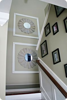 a staircase with pictures on the wall and a mirror hanging from the bannister