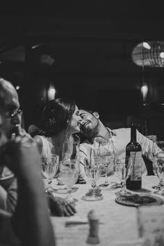 a man and woman kissing at a dinner table