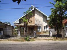 an old house is next to some trees on the side of the road in front of it