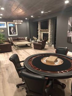 a living room filled with furniture and a table in front of a fire place on top of a hard wood floor