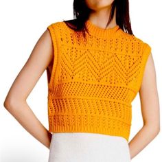 a woman wearing an orange sweater and white skirt