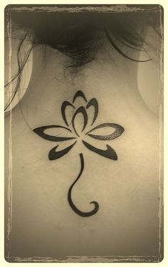 the back of a woman's neck with a flower tattoo on it