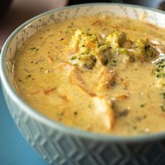 a bowl filled with broccoli soup on top of a blue tablecloth covered table