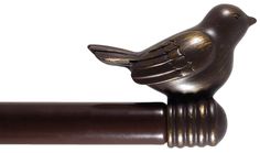 a bronze bird sitting on top of a wooden rod with a white background and brown trim