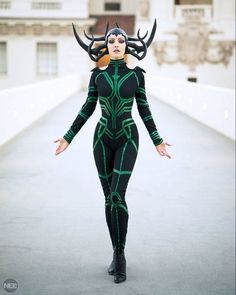 a woman dressed in black and green with horns on her head