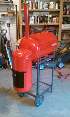 a red barbecue grill sitting on top of a metal cart in a garage next to other tools