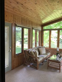 a living room filled with furniture and lots of wood paneling on the walls next to windows