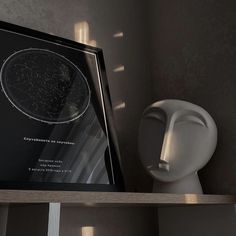 a framed photograph sitting on top of a wooden shelf next to a busturine