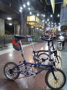 two bicycles parked next to each other on a sidewalk in front of a building at night