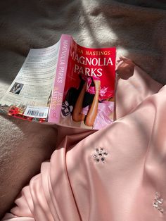 a pink dress laying on top of a bed next to a book titled the mascuola parks