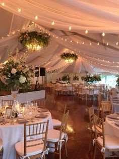 the inside of a tent with tables and chairs set up for a formal function at night