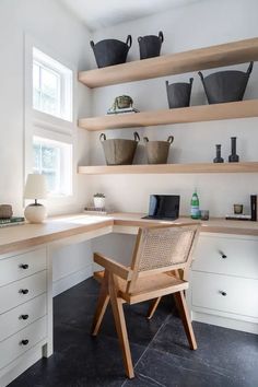 a chair sitting on top of a wooden desk next to a shelf filled with pots and pans