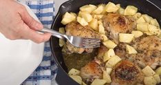 a person is holding a fork in a skillet with chicken and potatoes