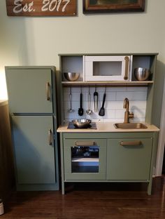 a toy kitchen with green cabinets and white walls