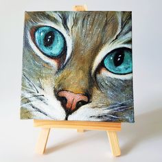 an easel with a painting of a cat's face on it