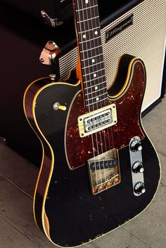 an electric guitar sitting on top of a hard wood floor next to a speaker and amp