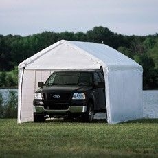 a black truck parked in front of a white tent on the side of a lake