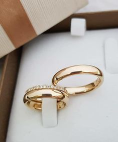 two gold wedding rings sitting in a box