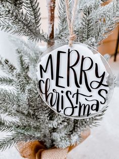 a merry christmas ornament hanging from a tree