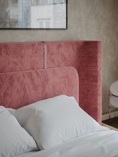 a pink headboard with white pillows in a bedroom