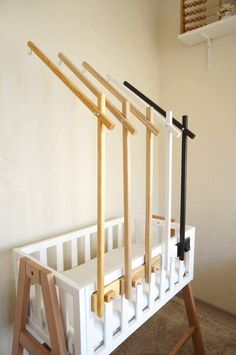 a white crib with three wooden bars on the top and two black ones on the bottom