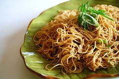 a green plate topped with noodles and vegetables