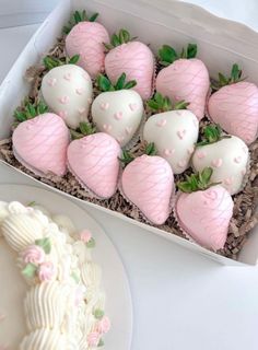 a box filled with white chocolate covered strawberries next to a plate full of cake