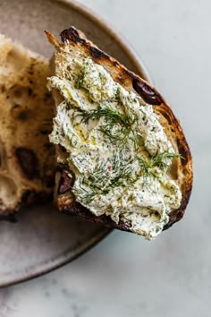 a piece of bread with cream cheese and herbs on it