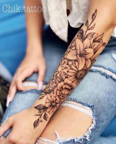 a woman's arm with flowers and leaves on it, in the middle of her leg