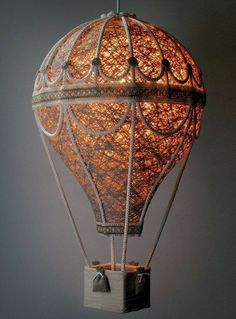 a lit up hot air balloon hanging from a ceiling fixture in the shape of a cage