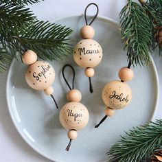 three wooden ornaments on a plate with pine branches