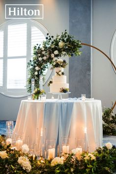 a table topped with a cake next to candles and flowers on top of a table