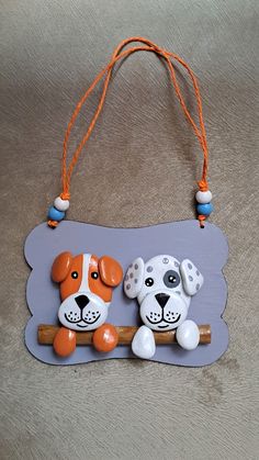 an orange and white dog hanging from a wooden sign on a gray background with beads