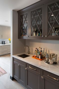 a kitchen with gray cabinets and marble counter tops