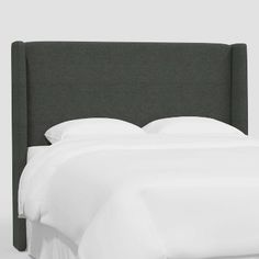 an upholstered headboard with white sheets and pillows on a bed in a bedroom