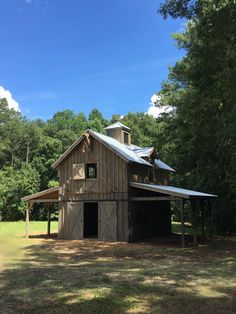 an old barn with a metal roof in the woods