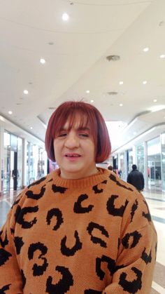 a woman with red hair wearing an animal print sweater