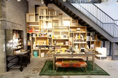 a room filled with lots of books on shelves next to a stair case and table