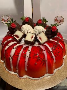 a red cake with white frosting and chocolate pieces on top, sitting on a gold platter