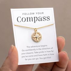 a person holding up a card with a compass charm on it