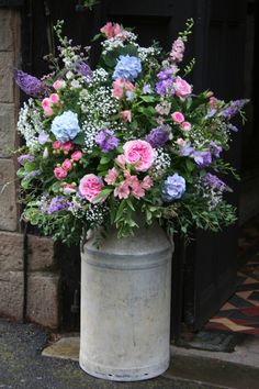 a bunch of flowers that are sitting in a vase on the ground near a fire place