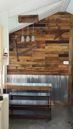 a wooden wall with some lights hanging from it's sides and a bench in the foreground