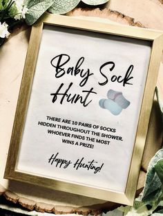 a baby sock hunt sign in a frame surrounded by greenery