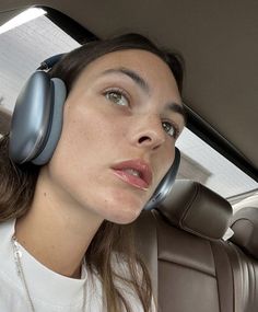 a woman sitting in the back seat of a car with headphones on her ears