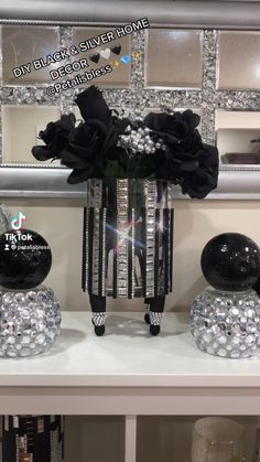 some black and white vases with flowers in them on a shelf next to a mirror